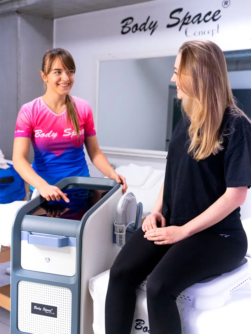 Terapeutka Body Space® obsługuje urządzenie do zabiegu, klientka siedzi na platformie zabiegowej