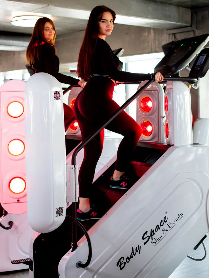 Dwie kobiety ćwiczące na InfraRed Stepper Body Space® z czerwonym światłem IR