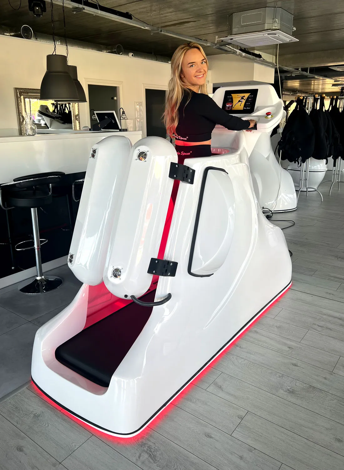 Kobieta ćwiczy na bieżni próżniowej Body Space z podczerwienią w studiu fitness
